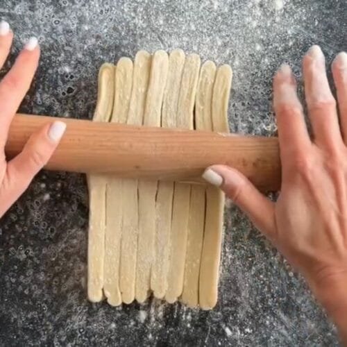 massa folhada cortada sendo aberta com o rolo