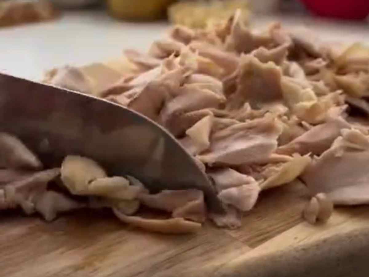 frango fatiado em uma tábua e uma faca de cozinha